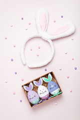 Funny kawaii bunny eggs and bunny rabbit ears for kids on pastel pink table top, Easter holiday concept. Easter decoration and set for creative activity for kids with crayons and notebook flat lay