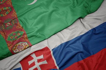 waving colorful flag of slovakia and national flag of turkmenistan.