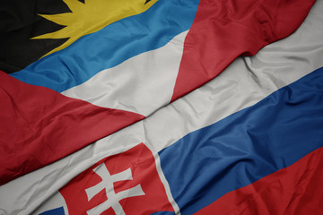 waving colorful flag of slovakia and national flag of antigua and barbuda.