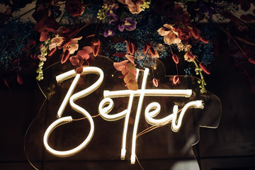 Better - neon sign on a wooden wall. Love concept	