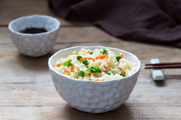 Vegetarian rice dish with vegetables and green peas on a wooden background.