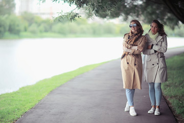 Obraz premium autumn fashion park girls two look / walk in a city park two glamorous fashionable girlfriends in a coat