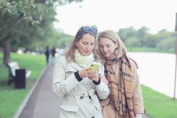 two girls look at the phone autumn walk / autumn city park coat, autumn fashion, style, look, clothes