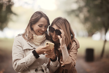 two girls look at the phone autumn walk / autumn city park coat, autumn fashion, style, look, clothes