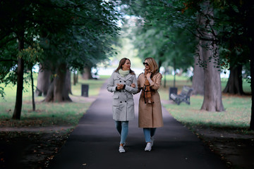 Fototapeta premium autumn fashion park girls two look / walk in a city park two glamorous fashionable girlfriends in a coat