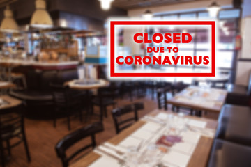 Closed due to coronavirus sign on defocused empty restaurant room