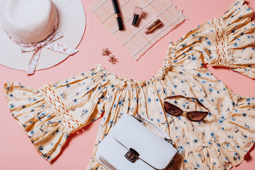Fashion female clothes and accessories for beach destinations or summer vacation. Flat lay with woman white clothing, straw hat and purse, make up on terracota background, woman travel fashion concept