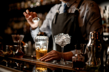 close-up glass with pieces of ice on bar counter.