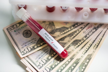 Corona virus covid-19 : closeup of blood sample vial on us dollar paper money bank notes. The concept of business and medicine in a global pandemic