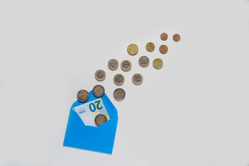 Blue envelope on a light background. A lot of coins, different denominations. Inside the envelope is a banknote of 20 euros.