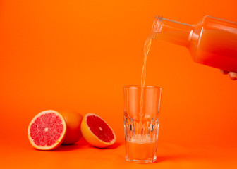 Pouring the grape juice in the glass over orange gradient background
