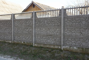 long private gray concrete fence in green vegetation on a rural street