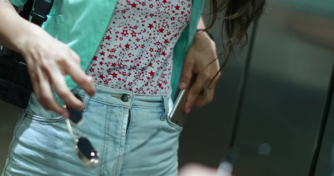 Woman putting away cellphone into pocket while in elevator