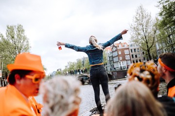 A young woman is living her best life on a canal party-boat in Amsterdam for King's Day.