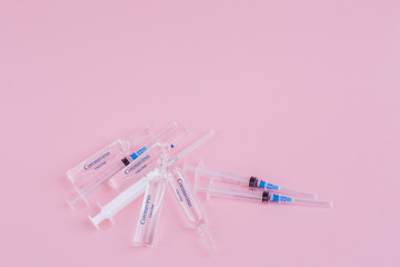 Plastic medical syringe and ampoules on a pink background.