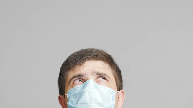 head of a young man in protective surgical mask looking up and following news, concept of health and medicine,emotions of confusion and perplexity