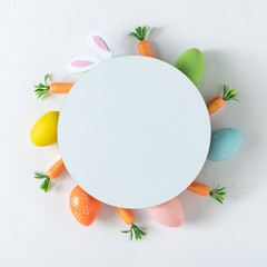 Creative layout made with colorful  Easter eggs and carrots and bunny ears. Minimal nature background. Spring holidays concept. Copy space paper card.