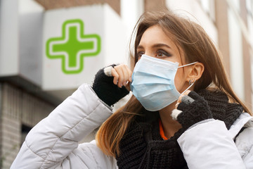 Woman in front of a german pharmacy with a face mask against infection and viruses such as flu,...