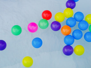 Many colored rubber balls float on the water.