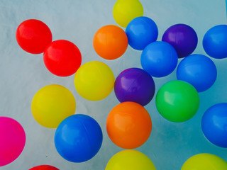 Many colored rubber balls float on the water.