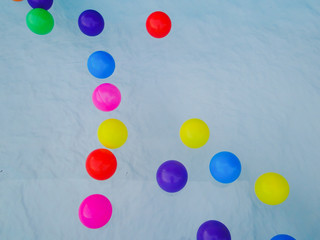 Many colored rubber balls float on the water.