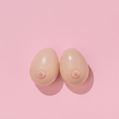 Creative Easter concept with eggs painted nipples on pastel pink and background. Minimal Easter Holiday idea. Woman's breasts made with Easter eggs.