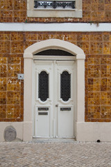 Lissabon, Portugal: Alte weisse Haustür umrahmt von traditionellen Fliesen Azulejos