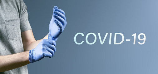 Covid-19 - Mann zieht Einweghandschuhe an um sich vor Virus zu schützen