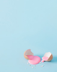 Eggshell with pastel pink paint. Creative copy space on blue background. Minimal Easter holiday...