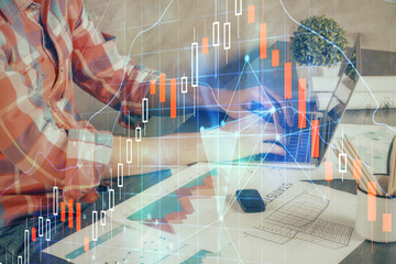 Double exposure of stock graph with businessman typing on computer in office on background. Concept...