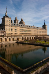 Fototapeta na wymiar Toma vertical de la fachada sur Real Monasterio de San Lorenzo de El Escorial reflejada en el estanque.