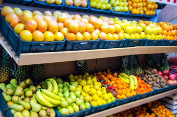 Fruit on a shelf in the market. Bananas, oranges, lemons, strawberries, apples, pineapples, kiwi are presented.