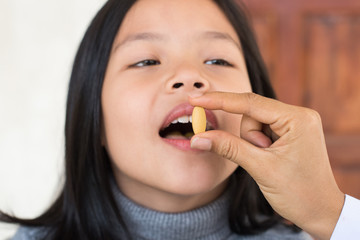 cute little girl having sick and happy to taking medicine in mouth. .Kid having pharmaceutical medical dose for pain relief or antibiotic medication curing from illness. healthcare,medicine concept .