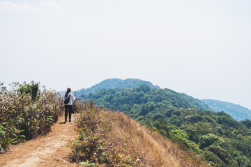 A woman hiking and standing on the top of mountains with blue sky background
