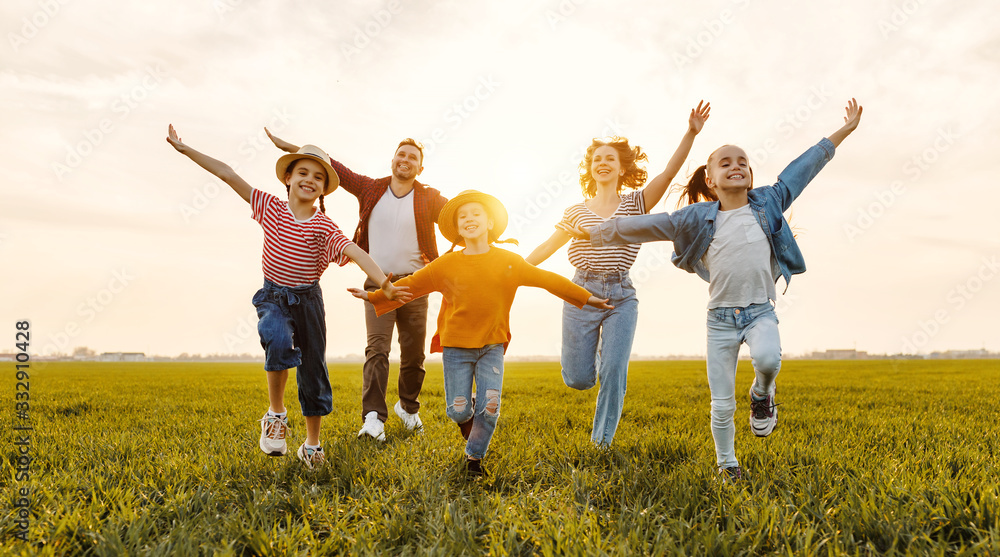 Wall mural happy family running in field in summer evening.