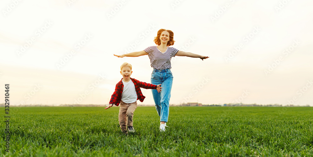 Wall mural happy woman with kid running in field.