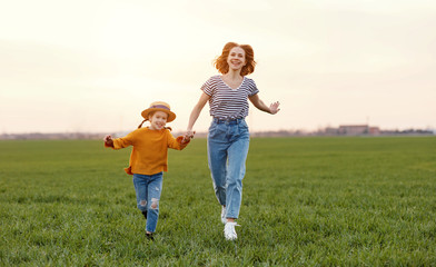 Fototapeta premium Happy woman with kid running in field.