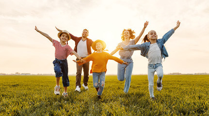 Happy family running in field in summer evening.