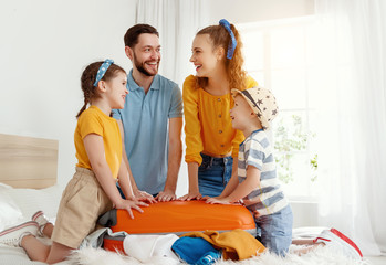 Excited family packing baggage on bed anticipating trip.