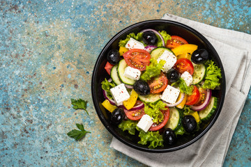 Greek salad in black plate on the table.