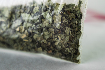 green dry crushed leaves (marijuana, tobacco) in a plastic bag