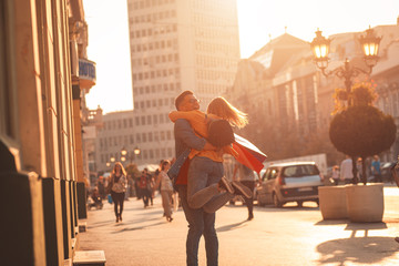 Smiling young couple walking at city street enjoying shopping together. - obrazy, fototapety, plakaty