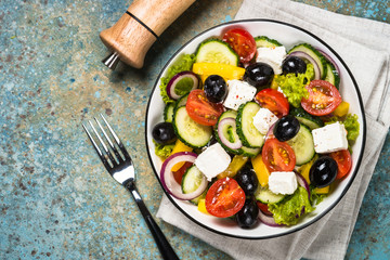 Greek salad in black plate on the table.