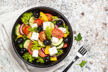 Greek salad in black plate on the table.