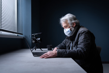 Senior man with face mask streaming a video online