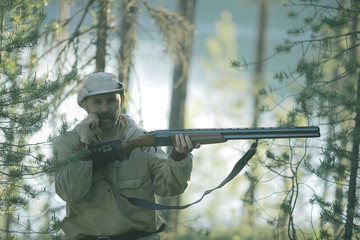 Fototapeta premium man goes hunting forest summer / landscape in the forest, huntsman with a hunting rifle hunts