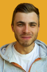 Fototapeta premium young hipster with a beard smiles and looks at the camera on a background of a yellow wall.