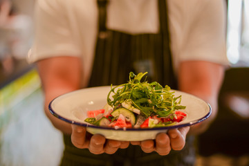 Waiter holding fresh vegetable organic salad, ready to serve. Vegan healthy diet, vegetarian food.
