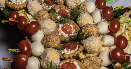 a variety of cold snacks on the table at parties; stuffed baskets, cheese balls, little tomatoes and more