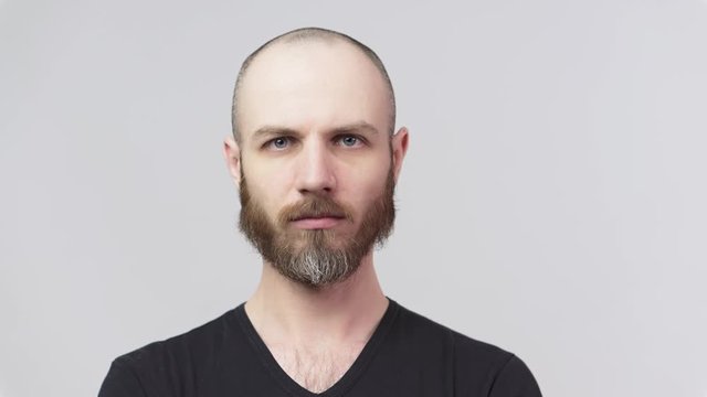 Strict bearded man looking at a camera over white background. Serious dissatisfied man. Concept of emotions.